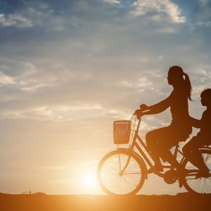 Silhouette of mother with her daughter and bicycle