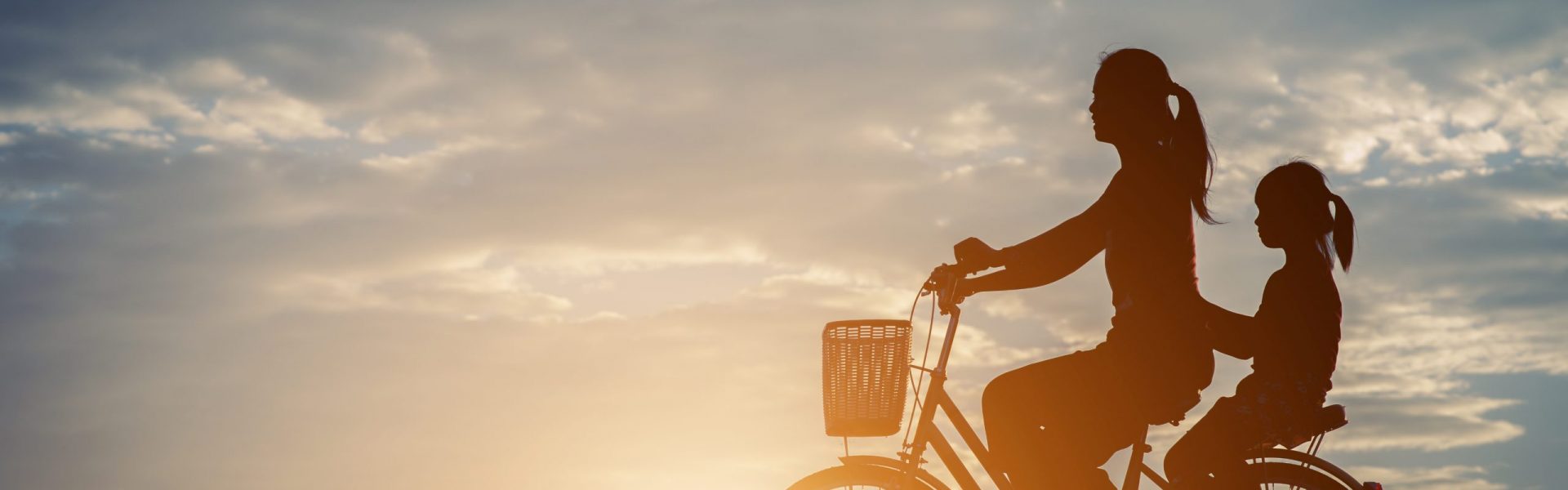 Silhouette of mother with her daughter and bicycle